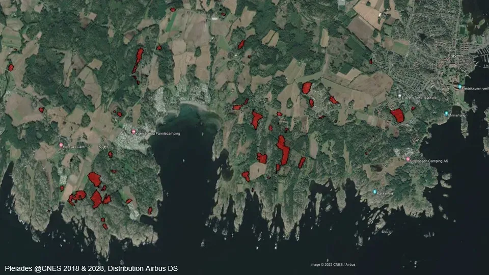Aerial photograph of a Norwegian coastline with red polygons drawn over the patches of ground that have been built on.