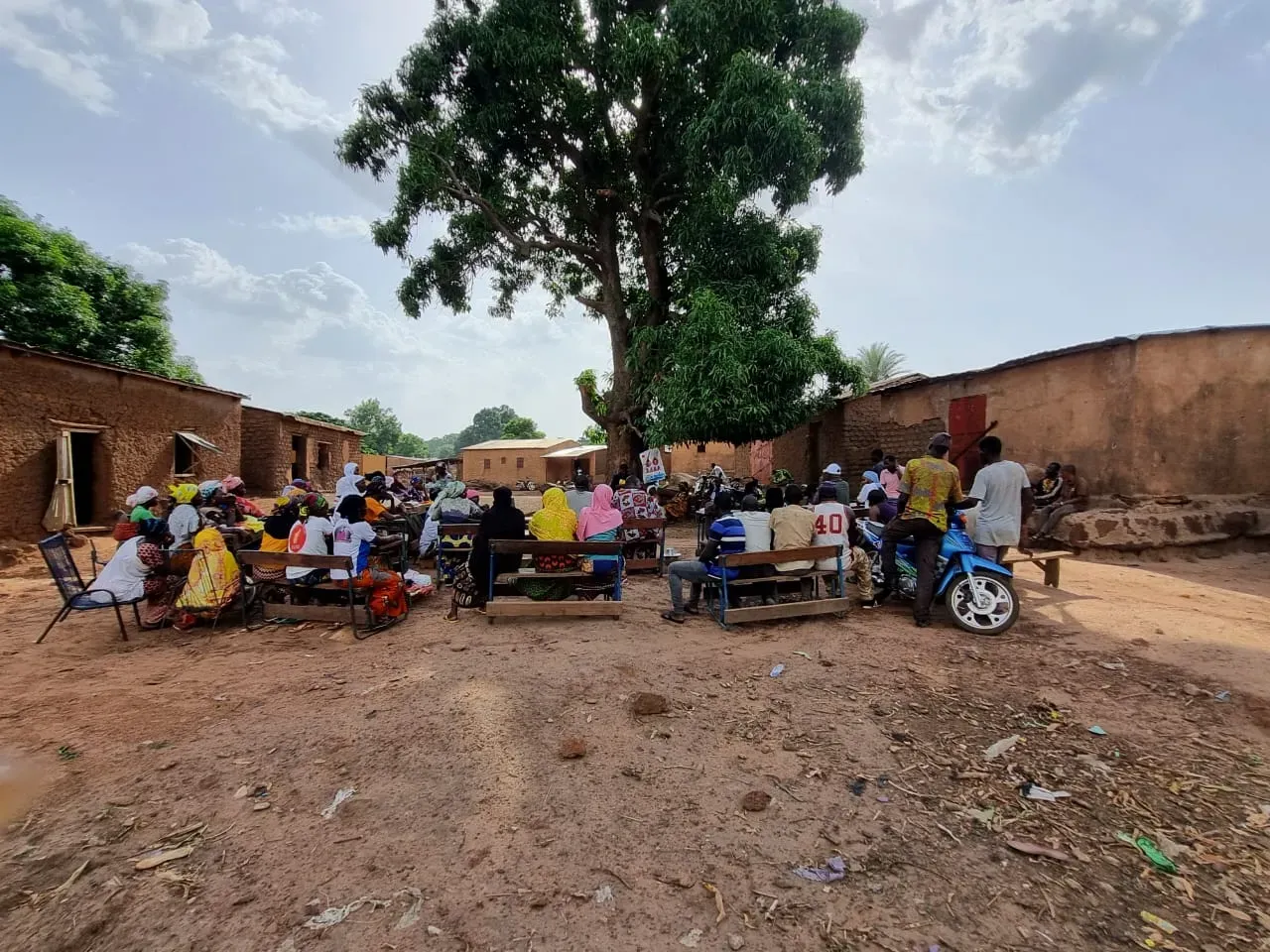 A community meeting held outdoors in a village.