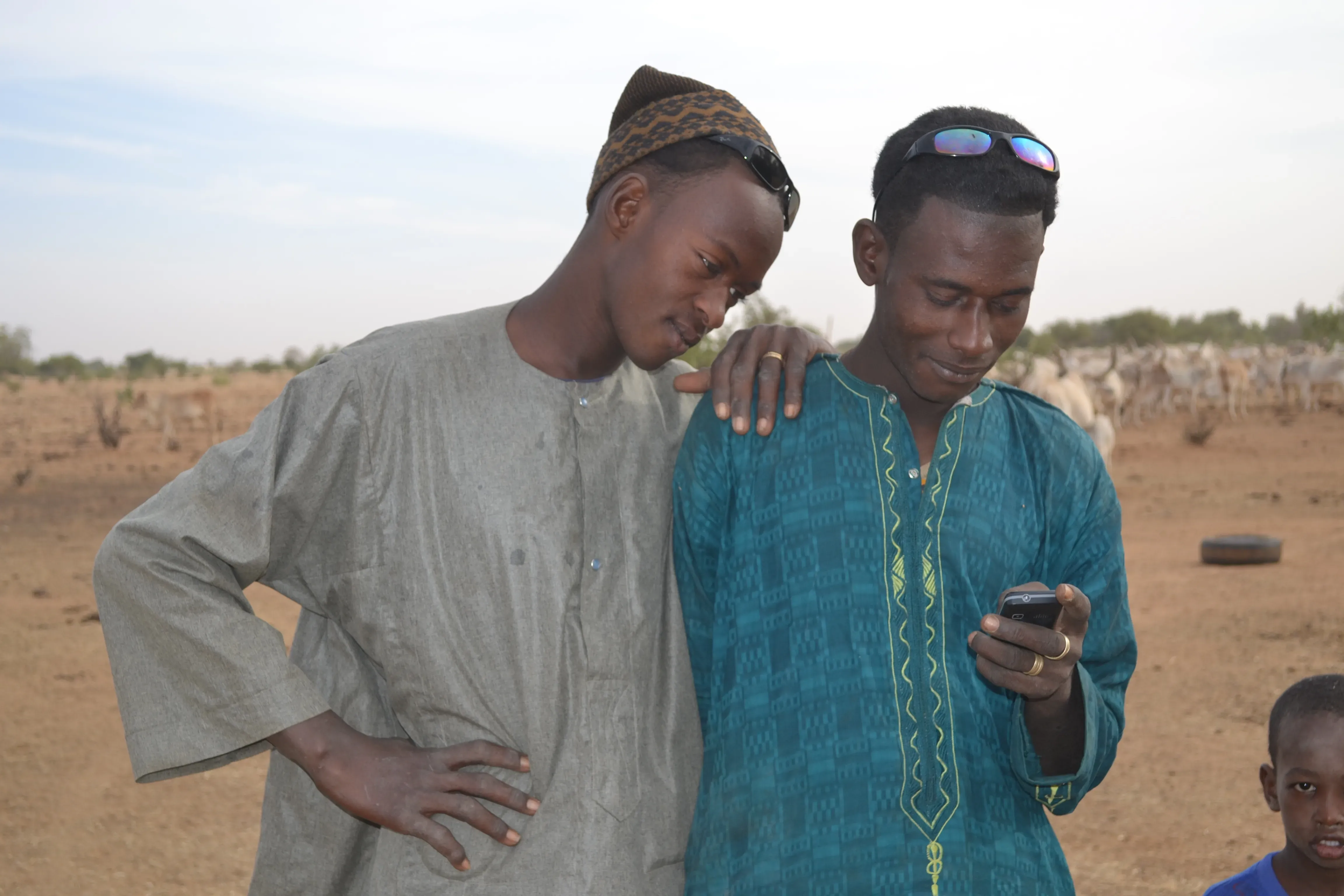 Two herders looking at a mobile phone.