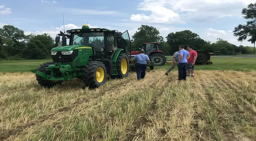 Tractor plowing a field with a cover crop in the foreground.