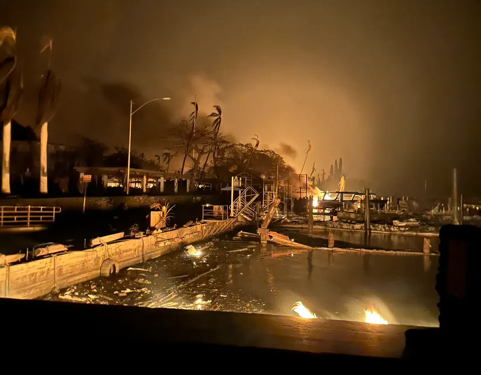 Wildfire smoke over a coastal town during rescue operations.