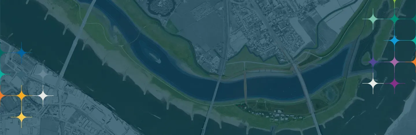 Satellite view of a wide river bending through a dense urban delta, its floodplain and engineered banks picked out in green against the grey of the built-up area.