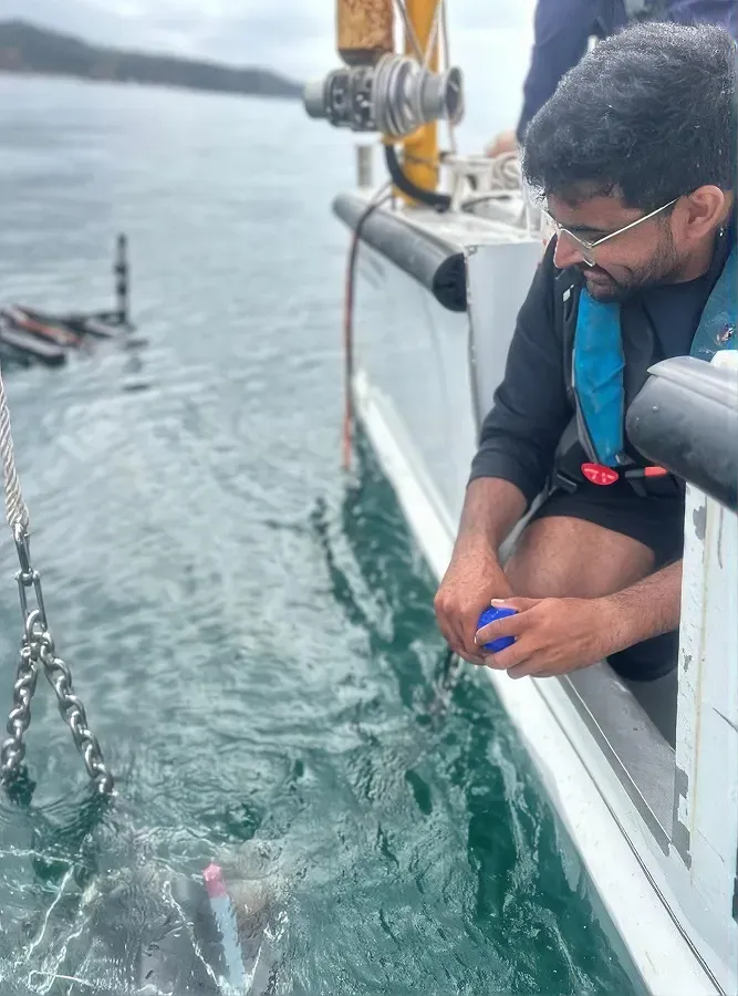 Researchers on a small boat lowering water quality and spectral instruments over the side while recording measurements.