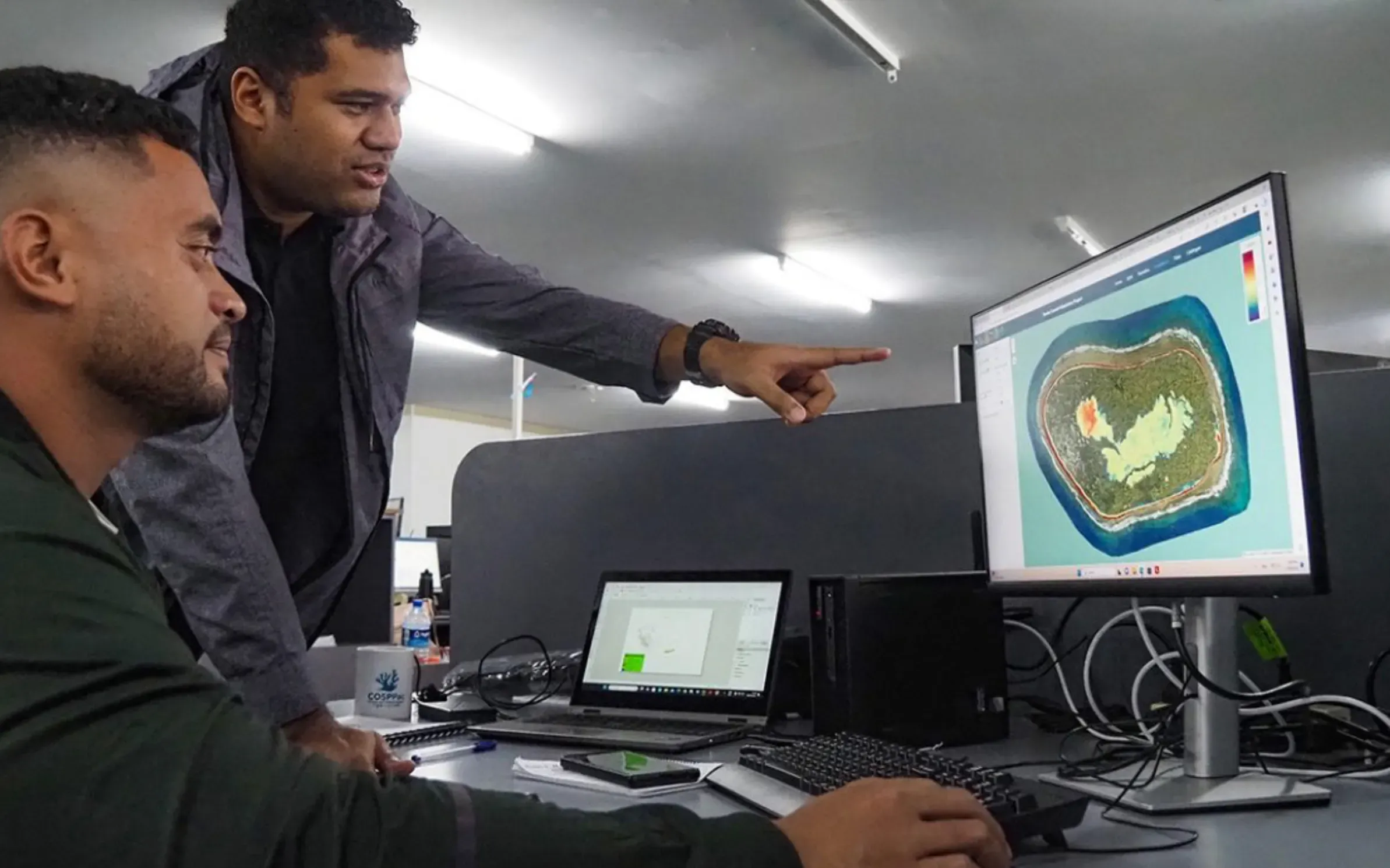 Two people at a screen working with LiDAR data in the coastal hazard platform.